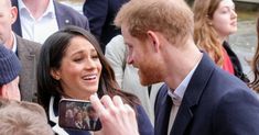 prince harry and his wife are surrounded by people