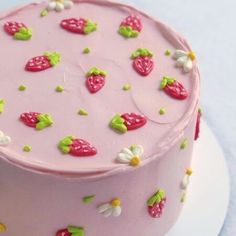 a pink cake decorated with strawberries and daisies