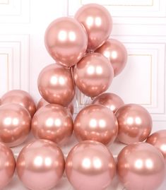 a bunch of pink balloons sitting on top of each other in front of a white wall