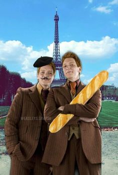 two men dressed in costumes standing next to the eiffel tower, holding bread