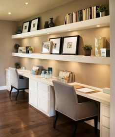 a home office with two desks and bookshelves on the wall above them