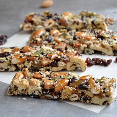 several pieces of fruit and nut bar on a sheet of parchment paper with one cut in half