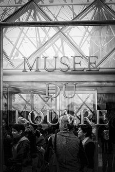 black and white photograph of people standing in front of a store window with the words museum du tour written on it