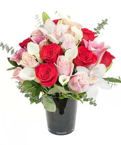 a black vase filled with red and white flowers