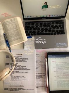 an open laptop computer sitting on top of a desk next to books and headphones