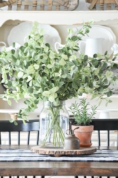 a vase filled with greenery sitting on top of a wooden table