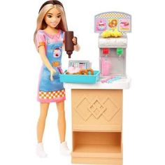 a barbie doll is cooking food in the kitchen and holding a tray with donuts on it