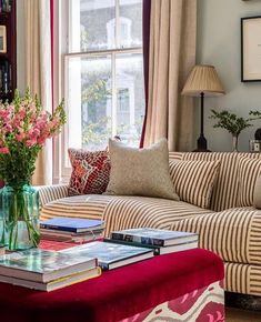 a living room filled with furniture and a vase full of flowers on top of a coffee table