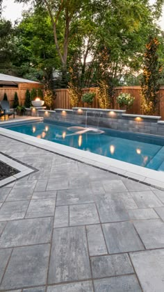 an empty swimming pool surrounded by trees and lights in the middle of a patio area