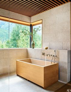 a bathroom with a large wooden bathtub next to a window that looks out onto the mountains