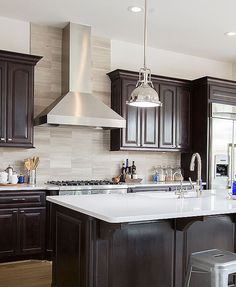 a kitchen with dark wood cabinets and white counter tops, an island in the middle