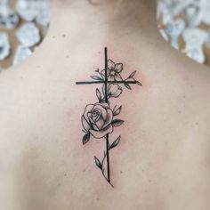 a woman with a cross and roses tattoo on her upper back shoulder, which is black and white