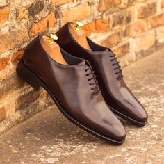 a pair of brown shoes sitting on top of a brick wall