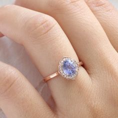 a woman's hand with a ring on it and an oval shaped blue stone in the middle