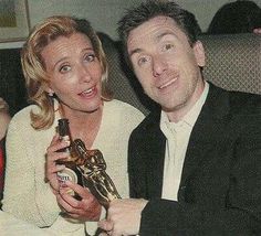 a man and woman sitting next to each other holding an award