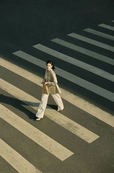 a woman walking across a cross walk in the street