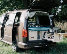 the back end of a van with an open hatchback door and bed in it