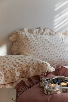 a tray with candles on top of a bed next to pillows and pillowcases