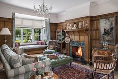 a living room filled with furniture and a fire place under a chandelier in front of a window