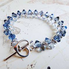 Elegant light blue sapphire and denim blue crystal bracelet is a great gift for women who love exquisite and sparkly blue jewelry. Handmade with Swarovski crystals and Swarovski rhinestone crowns and finished with a sterling silver toggle clasp.  A great gift for a mother of the bride or groom's mom. Luxe and gorgeous sapphire anniversary gift for your wife. A thoughtful gift for a woman born in September since blue sapphire is her birthstone. Bracelet Details: - Bracelet is .5 inches wide (1.27 Blue Crystal Bracelet With Sparkling Stones, Blue Faceted Crystal Bracelets, Blue Crystal Bracelets For Anniversary, Elegant Blue Faceted Crystal Bracelet, Adjustable Blue Crystal Bracelet For Anniversary, Handmade Blue Crystal Bracelet, Blue Crystal Bracelet, Sapphire Anniversary, Light Blue Sapphire