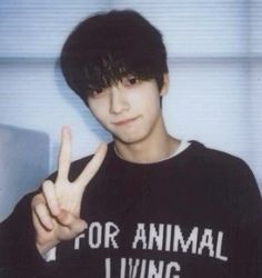 a young man is making the peace sign with his hand while wearing an animal living shirt