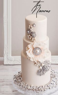 a three tiered wedding cake with pearls and flowers