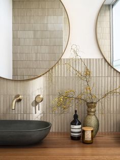 a bathroom with two round mirrors above the sink and a vase filled with flowers next to it