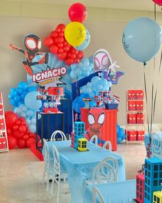 a party with balloons and spiderman decorations on the walls, table cloths and chairs