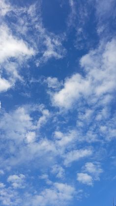 an airplane is flying high in the blue sky with white clouds and trees below it