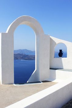 an arch with a vase in it on the side of a building next to water