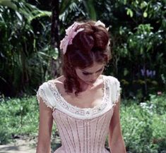 a woman in a pink dress is standing outside