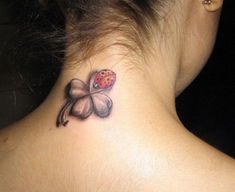 a ladybug tattoo on the back of a woman's neck