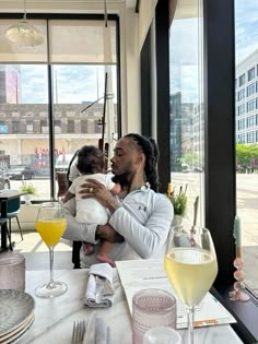 a man sitting at a table with a baby in his arms, holding an infant