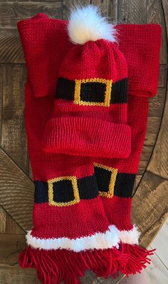 a red santa hat and scarf on top of a wooden chair