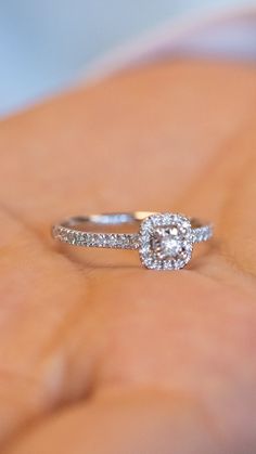 a close up of a person's hand holding a diamond ring