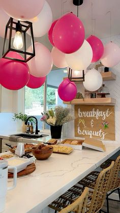 balloons are hanging from the ceiling above a kitchen counter with food and drinks on it