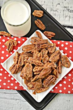 pecans on a white plate next to a glass of milk and red polka dot napkin