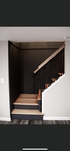 an empty room with stairs leading up to the second floor and another area that has been painted black