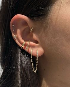 a woman's ear with two gold chains attached to the back of her ear