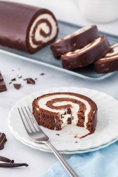 a piece of chocolate cake on a plate with a fork next to it and another slice in the background