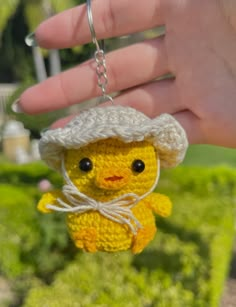 a small yellow stuffed animal wearing a white hat and holding a keychain in it's hand