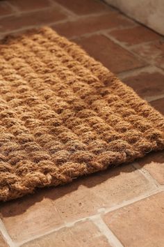 a brown rug sitting on top of a brick floor