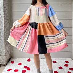 a woman standing in front of a wall wearing a colorful dress