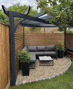 an outdoor seating area is shown in this backyard garden with wooden fence and black furniture