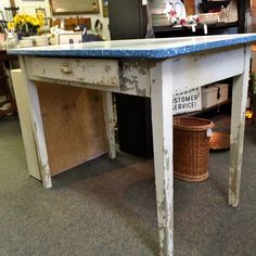 an old table with a basket underneath it in a room filled with furniture and other items