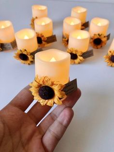 a hand holding a bunch of candles with sunflowers on them in the middle