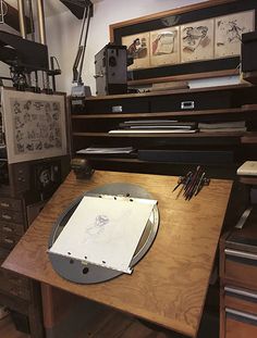 a wooden desk topped with lots of drawers and art work on it's sides