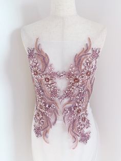 a white mannequin with pink and purple beading on it's chest