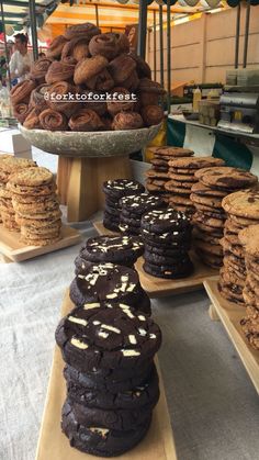 chocolate cookies and cookies are on display at a market stall with other desserts in the background