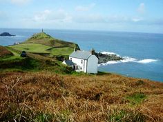 a white house sitting on top of a hill next to the ocean